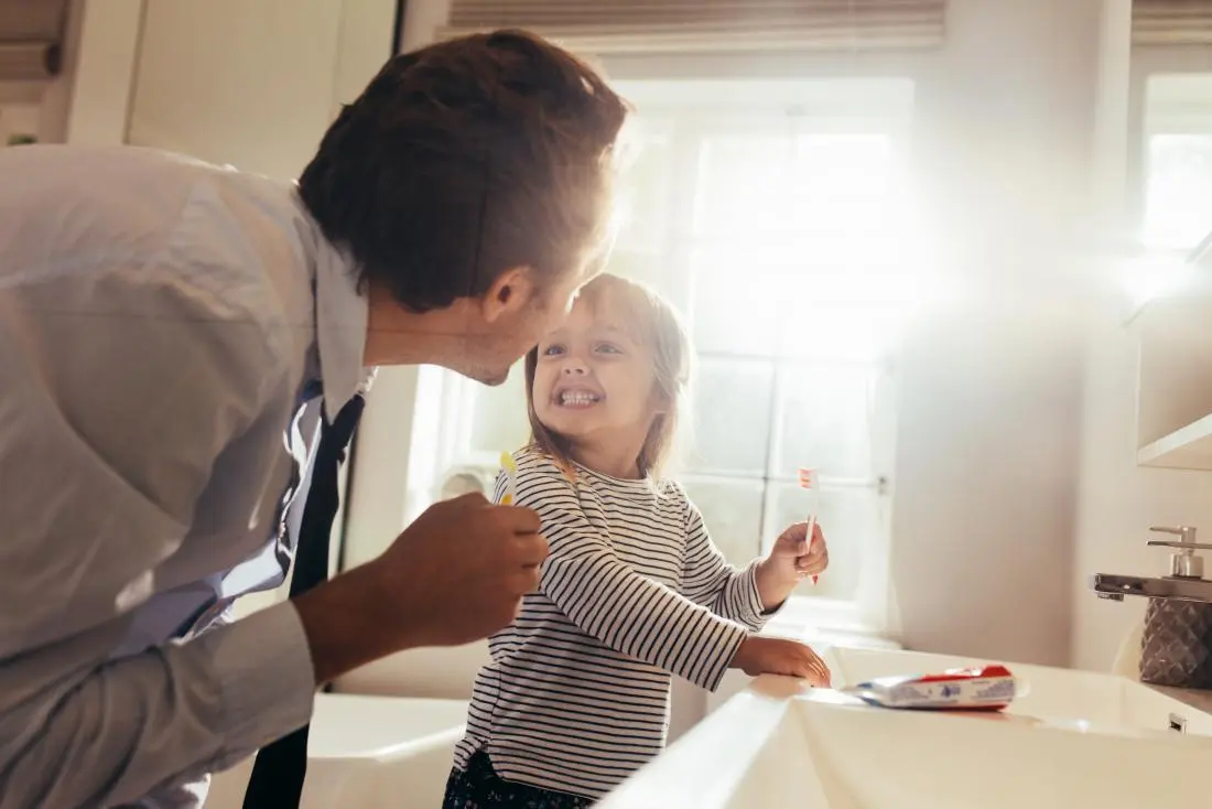 Father teaching child to brush teeth